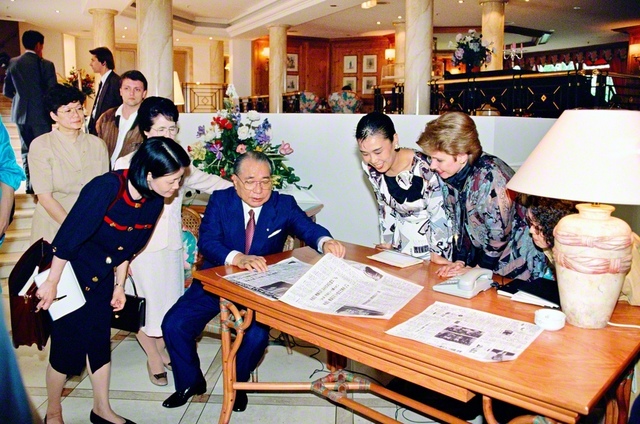 ヴァイツゼッカー大統領との会談を伝える聖教新聞の記事を見ながら、SGIメンバーを励ます池田先生。その誠実な振る舞いは、誰が相手でも変わらない（1991年6月、ドイツ・ボンで）
