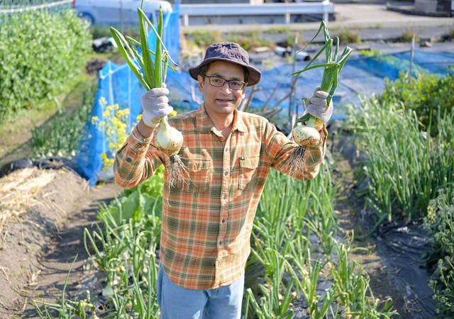 畑で収穫したタマネギを持って
