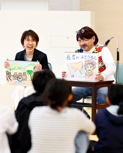 紙芝居を披露する“まさひろん”こと正広さん㊨。由美さんの飾らないリアクションがあってこそ笑いが成立する