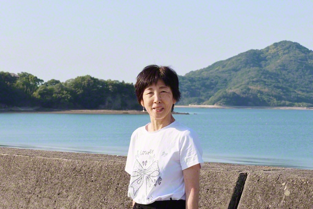 自慢の海を背景に立つ光岡左久子さん