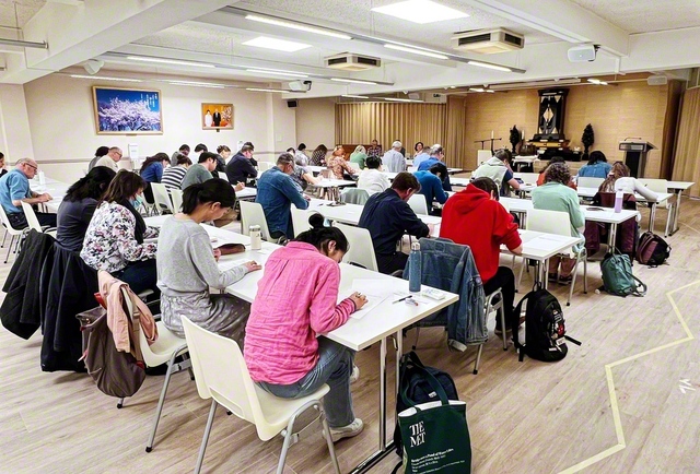 教学こそ人生を開く羅針盤！――忙しい合間を縫って人間主義の哲学を学んできた友が、真剣なまなざしで答案用紙に向かう（ベルギー文化会館で）