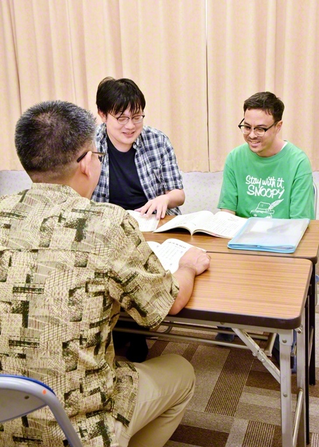試験直前まで教材を開き、復習する友。沖縄戸田県のある男子部員は、ひきこもりの時期があった。同志に励まされて受験を決意。「約20年ぶりの勉強でした。自分が前進していると実感し、楽しかった」と笑顔で語った（沖縄市の中頭文化会館で）