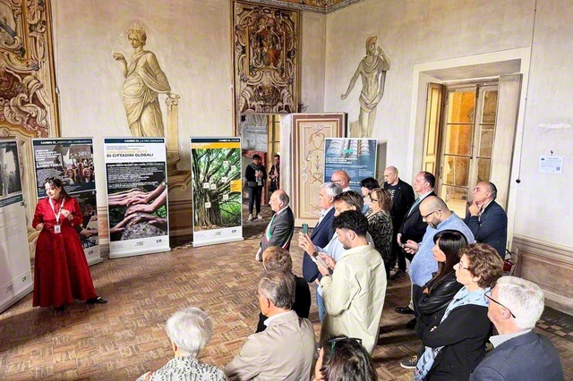 「生の継承」展の見学の様子。来場者がボランティアスタッフの説明に耳を傾ける（ロンバルディア州カステッレット・ディ・ブランドゥッツォ市内で）