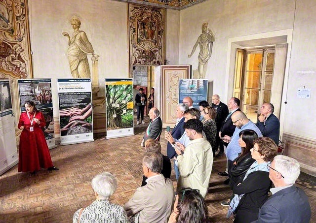 「生の継承」展の見学の様子。来場者がボランティアスタッフの説明に耳を傾ける（ロンバルディア州カステッレット・ディ・ブランドゥッツォ市内で）