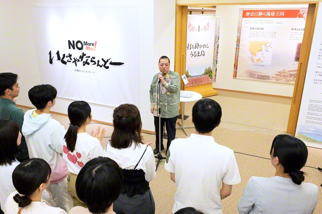「いくさやならんどー」展のオープニングセレモニーで作家の佐藤優氏があいさつ。パネルや映像、平和の心を伝える品々が展示されている（東京・新宿区の創価文化センターで）