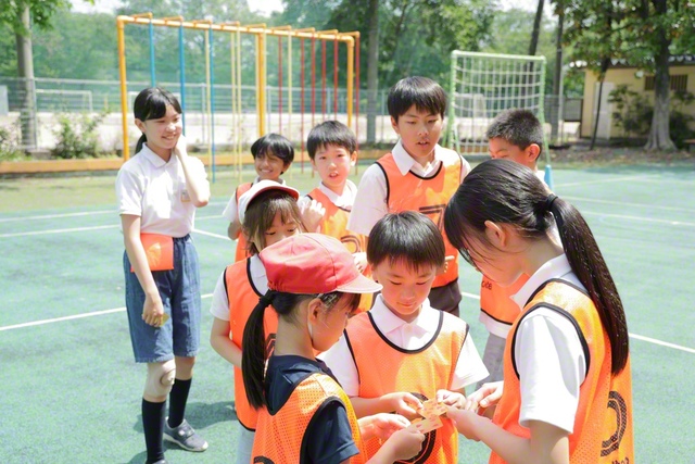 東京創価小学校には、「フレンドリー班」という1～6年生までが所属する縦割り班もあります。先月末の授業参観の折には、班の先輩たちが考えたレクリエーションで楽しむ時間も。この写真は、トランプの数で競い合う鬼ごっこの一場面