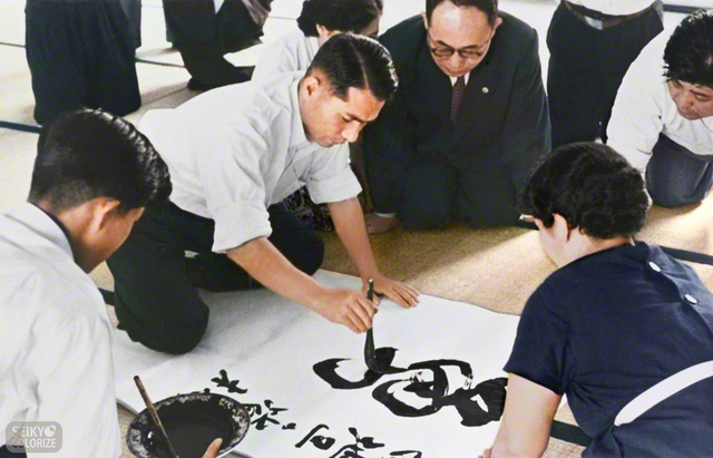 1956年の「大阪の戦い」の折、旧関西本部で「勇戦」と大書する池田先生（※今回掲載されているカットは、モノクロ〈白黒〉でしか見られなかった聖教新聞社所蔵の写真を、編集部の責任のもと、AI〈人工知能〉を活用してカラー化したものです）