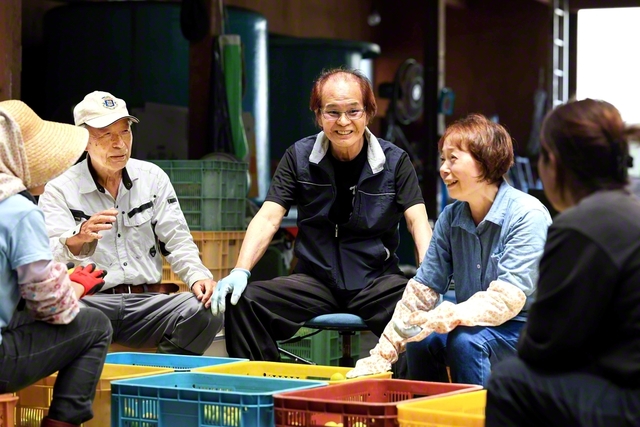 「雨風を耐え抜いて、きちっと実をならす。その生命力に負けんよう、私らも頑張りますよ」と竹田和久さん（右から3人目）と妻・圭子さん（同2人目）