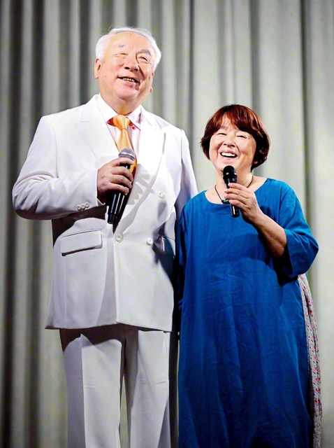 洋二さん㊧と優子さんが仲良くマイクを握る。夫婦の信心で「人生に行き詰まりはない」ことを証明してきた