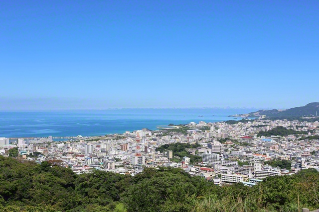 名護の市街地と名護湾。中央左に見える名護漁港の辺りは昔、浜辺だった。池田先生は1969年2月、そこで名護の友と出会いを結んだ