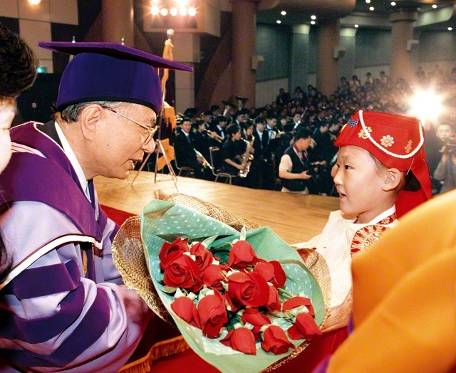 1998年5月、韓国・ソウルの慶熙大学での名誉哲学博士号の授与式。伝統衣装を着た子どもから、池田先生に祝福の花束が贈られた