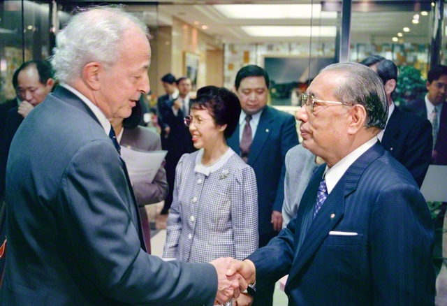 池田先生と生命倫理学者のギー・ブルジョ博士が友好の握手を交わす。語らいでは、科学や哲学に基づいた健康観を確立し、万人に説く必要があるとの意見で一致した（1994年12月、東京・信濃町の聖教新聞本社〈当時〉で）