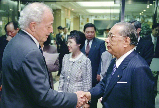 池田先生と生命倫理学者のギー・ブルジョ博士が友好の握手を交わす。語らいでは、科学や哲学に基づいた健康観を確立し、万人に説く必要があるとの意見で一致した（1994年12月、東京・信濃町の聖教新聞本社〈当時〉で）