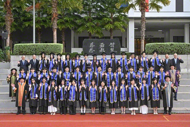 5カ国から集い合った卒業生が記念のカメラに。創立者・池田先生の筆による「智慧」「勇気」「慈悲」の文字が刻まれた「建学の精神」の碑を背にして