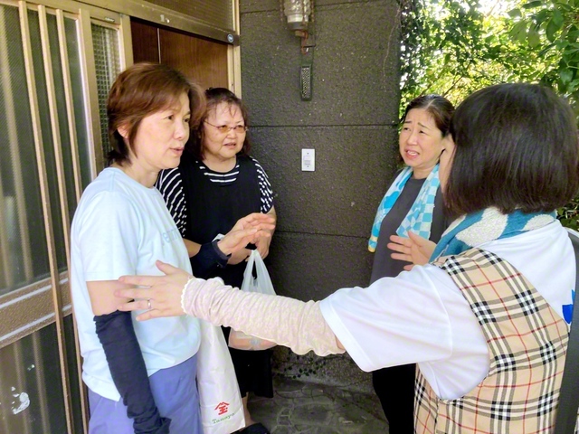 志賀県女性部長（右から2人目）らが増住さん（同3人目）と、近くに住む地区副女性部長の宮本洋子さん（左端）を励ます