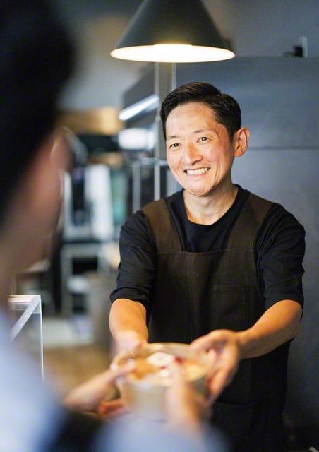 弁当を手渡す多田さん。「帰って開いて食べてハッピーになってほしい」