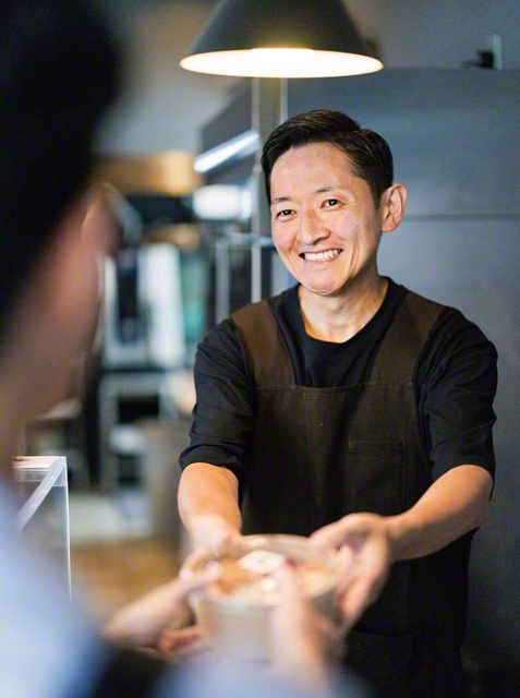 弁当を手渡す多田さん。「帰って開けて食べてハッピーになってほしい」