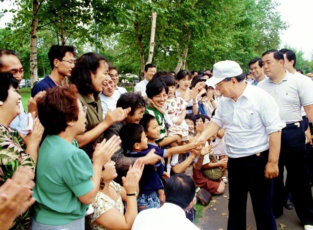 尊き後継の友に、皆で限りない励ましを！――子どもたちを見つけ、優しく握手を交わす池田先生。多宝の友らも笑顔で見守る（1991年8月、北海道・函館研修道場で）