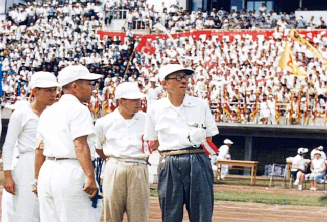 1957年9月8日、「若人の祭典」で青年の敢闘を見守る戸田先生と池田先生（左から2人目）。閉会式で、戸田先生は「原水爆禁止宣言」を発表した（横浜・三ツ沢の競技場で）