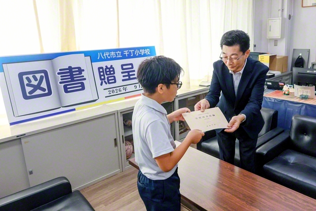 中山熊本総県長㊨から児童代表に目録が手渡された（熊本・八代市の千丁小学校で）