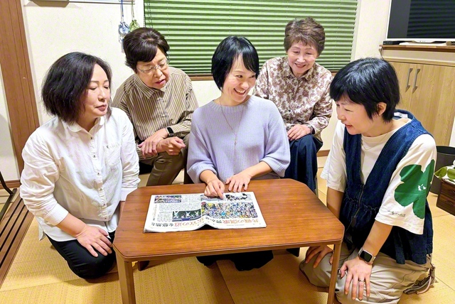 堤西地区の未来部員がたくさん写った「PEACE　PRIDE」の聖教紙面を見ながら語らう元谷さん（中央）ら。世代を超えた「総合力」で、誰もが安心して集える居場所をつくる（川崎市多摩区内で）