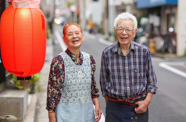 赤ちょうちんの向こうで、笑顔をともし続けた宍戸秀夫さん㊨・信子さん夫婦。居酒屋「茶や」の常連客は「大将とおかみに会いたくて、みんなこの店に来るんだから」と
