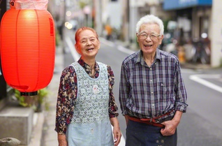 赤ちょうちんの向こうで、笑顔をともし続けた宍戸秀夫さん㊨・信子さん夫婦。居酒屋「茶や」の常連客は「大将とおかみに会いたくて、みんなこの店に来るんだから」と