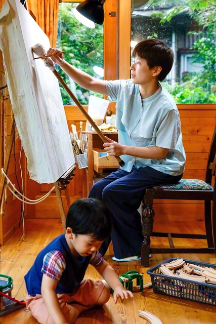 あかりさん㊨は「描く時より、絵を見て喜んでもらえる時の方がうれしい」と。一瞬の感動のために、何度も色を重ねる。おもちゃで遊ぶ長男・あおばくんの隣には、優しく、強い母がいる
