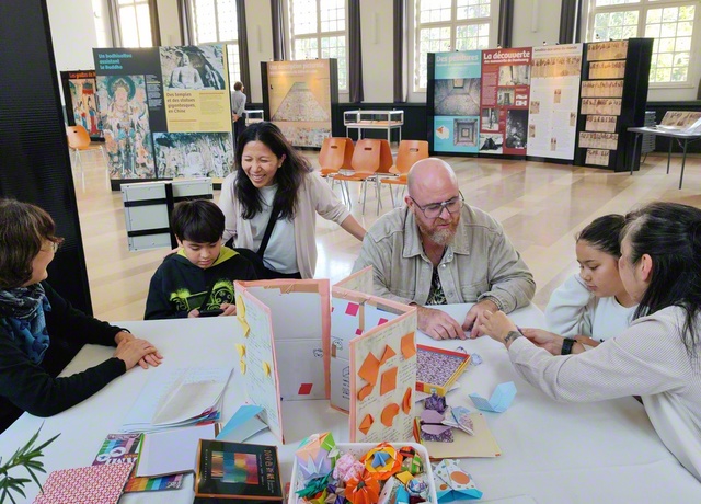 展示スタッフと来場した子どもたちが、共に折り紙を楽しむ場面も