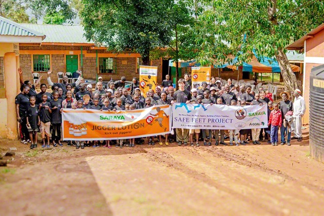 「SAFE　FEET　PROJECT」に参加した人たちが記念のカメラに（ケニア・エスンバ村で。写真提供＝「Waka　Waka　Kenya」）