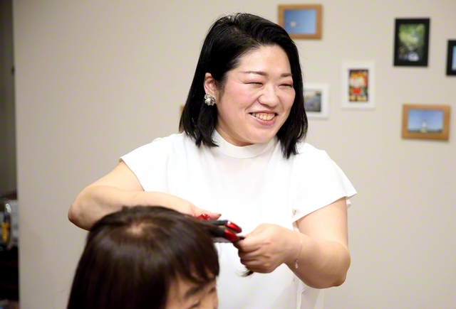 客と和やかに語らいながらヘアアイロンをかける坂下さん