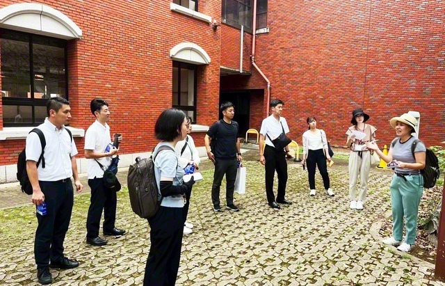 山里小学校で当時の歴史についてガイドの声に耳を傾けるメンバー（8月30日、長崎市で）