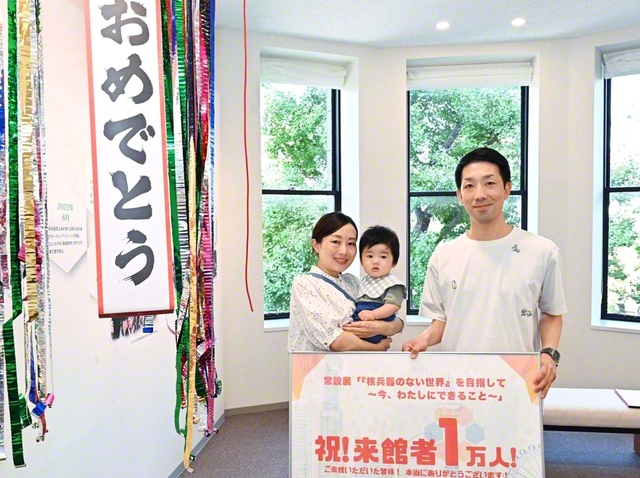 1万人目の来館者となった片川優さん㊧が、家族と記念のカメラに
