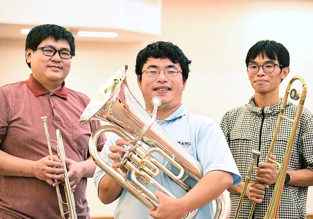 音楽隊の仲間と切磋琢磨する堀内さん㊥。「仕事に学会活動にと忙しい日々ですが、充実しています」と語る笑顔が、まぶしい