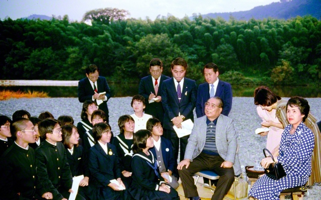 錦帯橋が架かる錦川の河原で、中・高等部の「新世紀会」の友と語らう池田先生ご夫妻(1984年10月24日、岩国市内で)