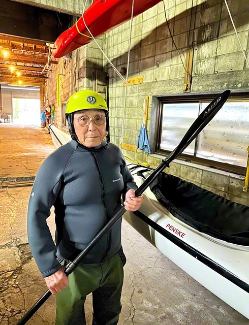 福士さんがパドルを手に。自宅倉庫にはカヤックが並ぶ