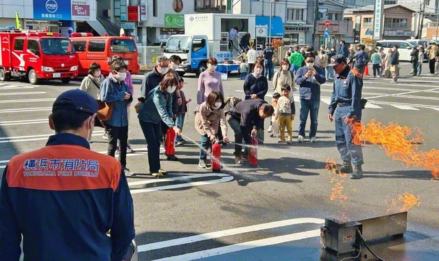 駐車場を使用して地震と消火の体験を。参加者は真剣な表情で取り組んでいた（1日、緑文化会館で）
