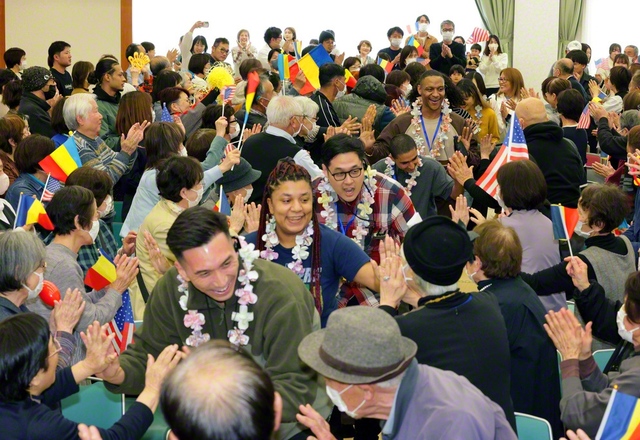 アメリカ青年部メンバーと笑顔でハイタッチ。三色旗などを振りながら盛大に歓迎した（下関文化会館で）