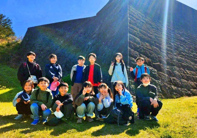 青葉少年少女合唱団の友が“団結の象徴”である石垣の前で記念のカメラに