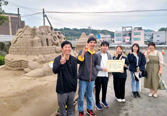 南薩桜華圏の青年世代の代表が「砂の祭典」に出展した。砂像の題名は「世界平和への祈りを音楽の歓喜に込めて」。友のけなげな姿に主催者から「ぜひ来年も」と早速の創作依頼が（3日、南さつま市で）