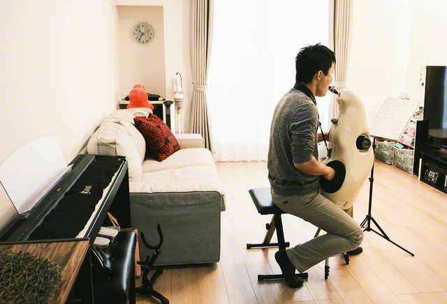 アルトサックスに消音器を取り付け、自宅で練習に励む