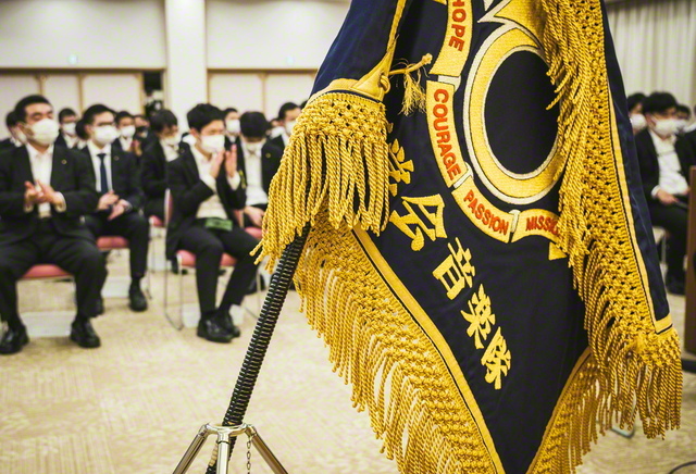 全日本吹奏楽コンクールに挑んだ友と音楽隊旗（10月31日、四国池田文化会館で）。英語で「希望」「勇気」「情熱」「使命」の文字が刻まれている。誇り高き音楽隊旗の前で、代表者が「音楽隊訓」を朗読。師の心をわが胸に燃やして