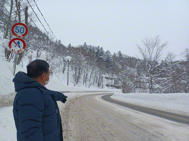 事故現場を案内する白山信之さん（1月）。写真から見て反対車線から大橋住職の車が猛スピードでセンターラインを越えて白山さんのトラックに正面衝突してきた