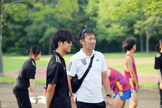 榎木監督㊨と談笑する安達主務。常に監督とのコミュニケーションを欠かさない