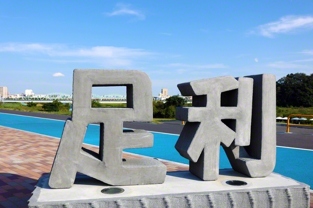 1級河川・渡良瀬川のほとりに立つ「足利」のモニュメント。奥には歌手の森高千里さんの名曲にも歌われた「渡良瀬橋」が見える
　