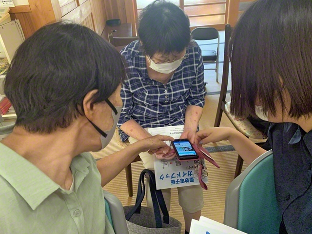 「文字拡大機能はこれよ」と参加者で互いに操作方法を教え合う（同）