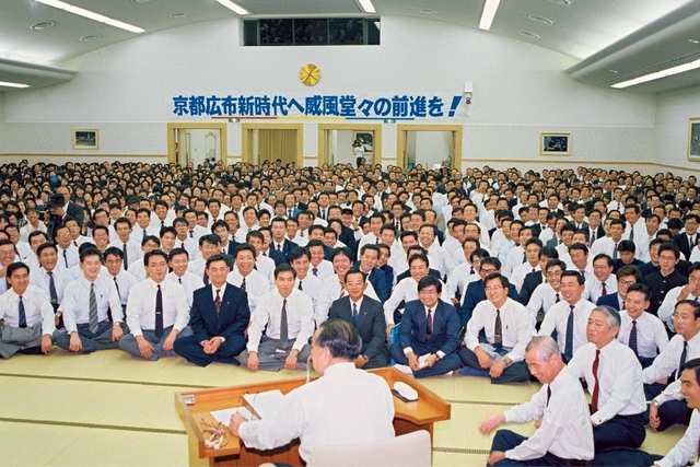 「すばらしき、また意義ある『京都平和講堂』の落成、まことにおめでとうございます」――「京都記念幹部会」の席上、同志を祝福する池田先生。「わが地域を心から愛し誇りとしながら、地域に最大に貢献していこう――こう決めて前進していく人こそ、人生に確かな『幸福』と『広宣流布』の歴史を築くことができる」と語った。この日は、後に「京都の日」と制定された（1989年10月18日、京都平和講堂）
