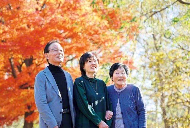 いつも家事等を担って本山さん㊥を支えてくれる夫・六郎さん㊧（壮年部員）や、信心を教えてくれた母・テイさん㊨（地区副女性部長）と。遠方で奮闘する最愛の息子たちは、本山さん夫妻に箱根や大阪万博への旅行をプレゼントしてくれた。東京の美術大学で学んだ本山さんは、最近、施設の利用者たちとちぎり絵の制作に励むなど、全ての経験が無駄なく生かされることを実感している