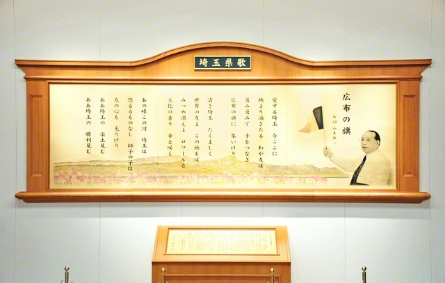 埼玉文化会館内に設置された県歌「広布の旗」の歌碑。そこには、1991年12月8日の本部幹部会で、同志と共に三色旗を手に学会歌を歌う池田先生の姿が刻まれている