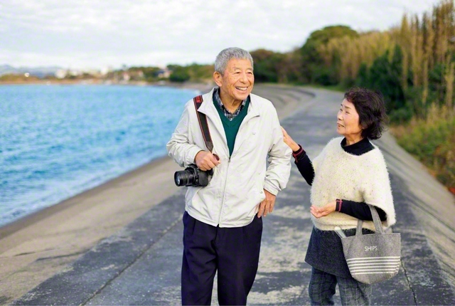かなたに富士山を望む館山湾沿い。愛用のカメラを手に、妻・和江さん㊨（県女性部主事）と歩く山口さん。連休を利用して国内外を飛び回り、美しい原風景にカメラを向けてきた。JR退職後は実家の農家を継ぎ、現在は花卉栽培などを行う。“千葉通信員の重鎮”は、皆に安心を与える柔和な笑顔で、今も取材を重ねている